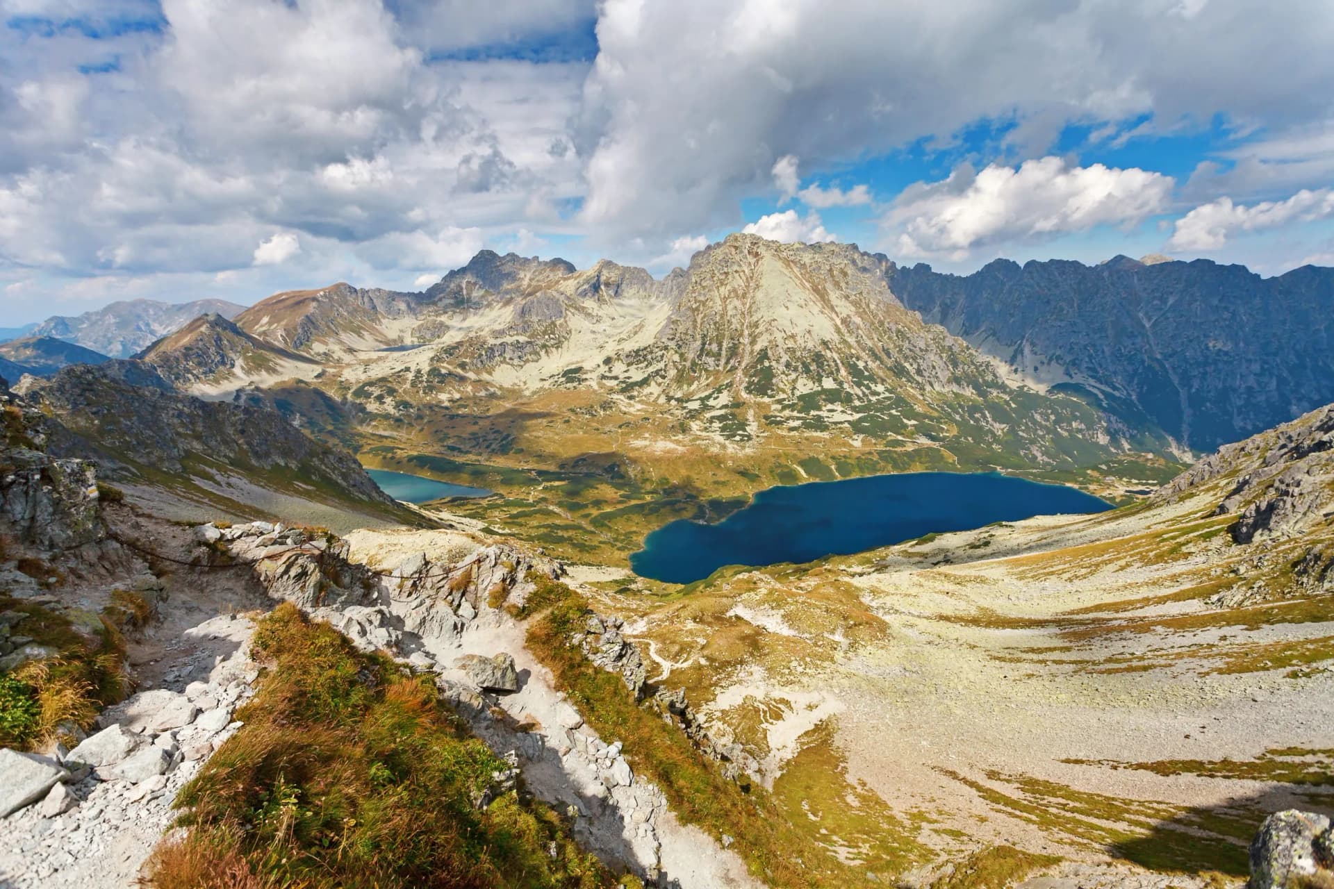 Hiking trail overlooking Five Ponds Valley and dark blue alpine lakes in the Tatras mountains.