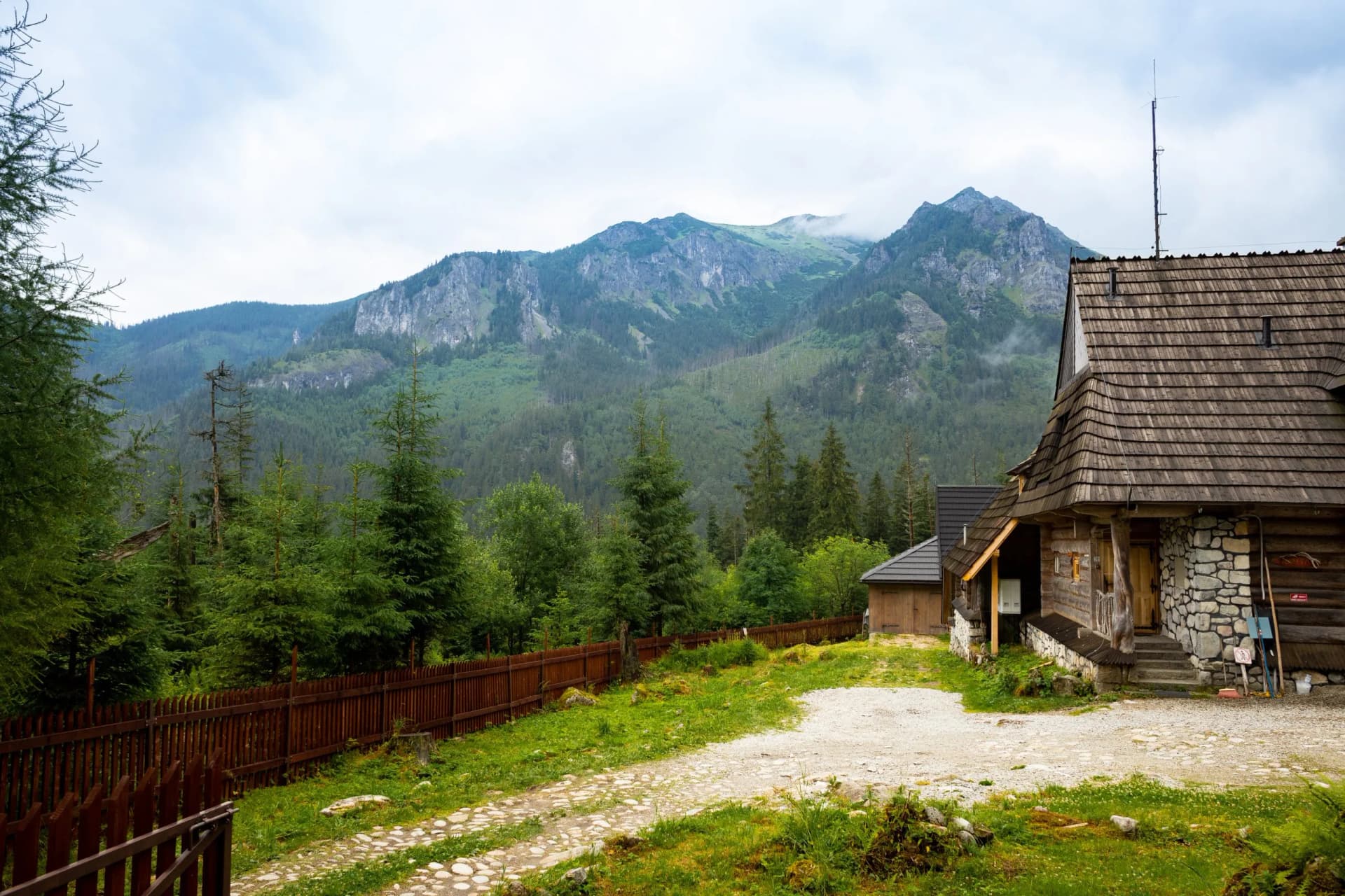 Wooden mountain hut near forest with rocky peaks in the background, Morskie Oko Tatras.