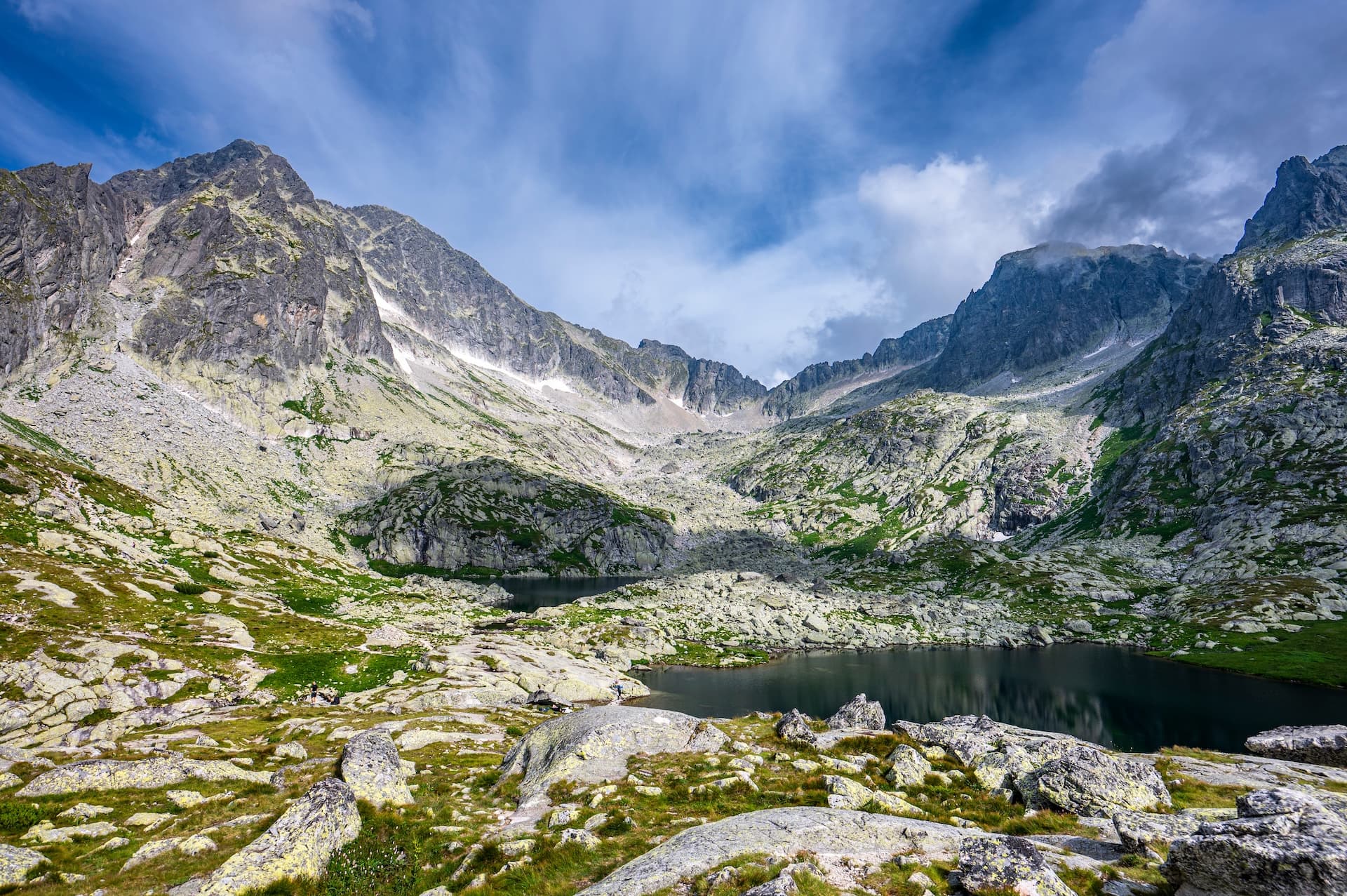 Rocky alpine landscape with dark mountain lakes under a dramatic blue sky in the High Tatras.