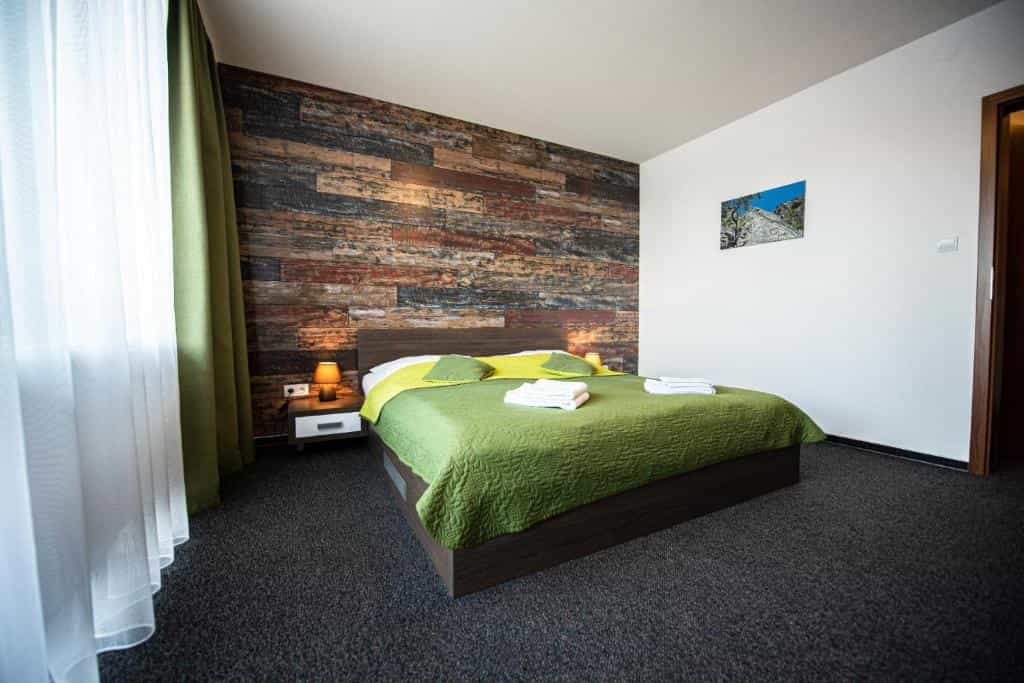 Bedroom with green bedding, wood accent wall, and sheer white curtains