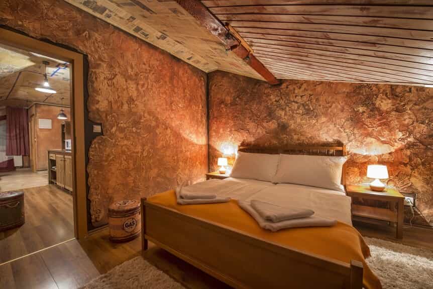 Cozy bedroom with textured orange walls, wooden bed, and lamps, near Poprad.
